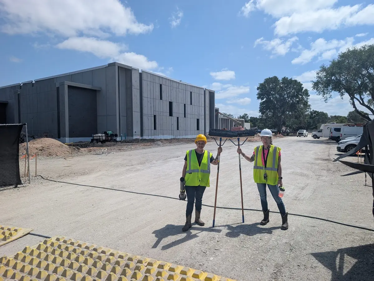 Orchid Cleaning crew in safety vests and hard hats with push brooms at a commercial construction site