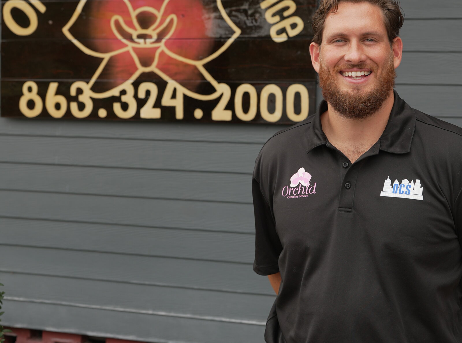 Joey Maher in front of the Orchid Cleaning Service sign